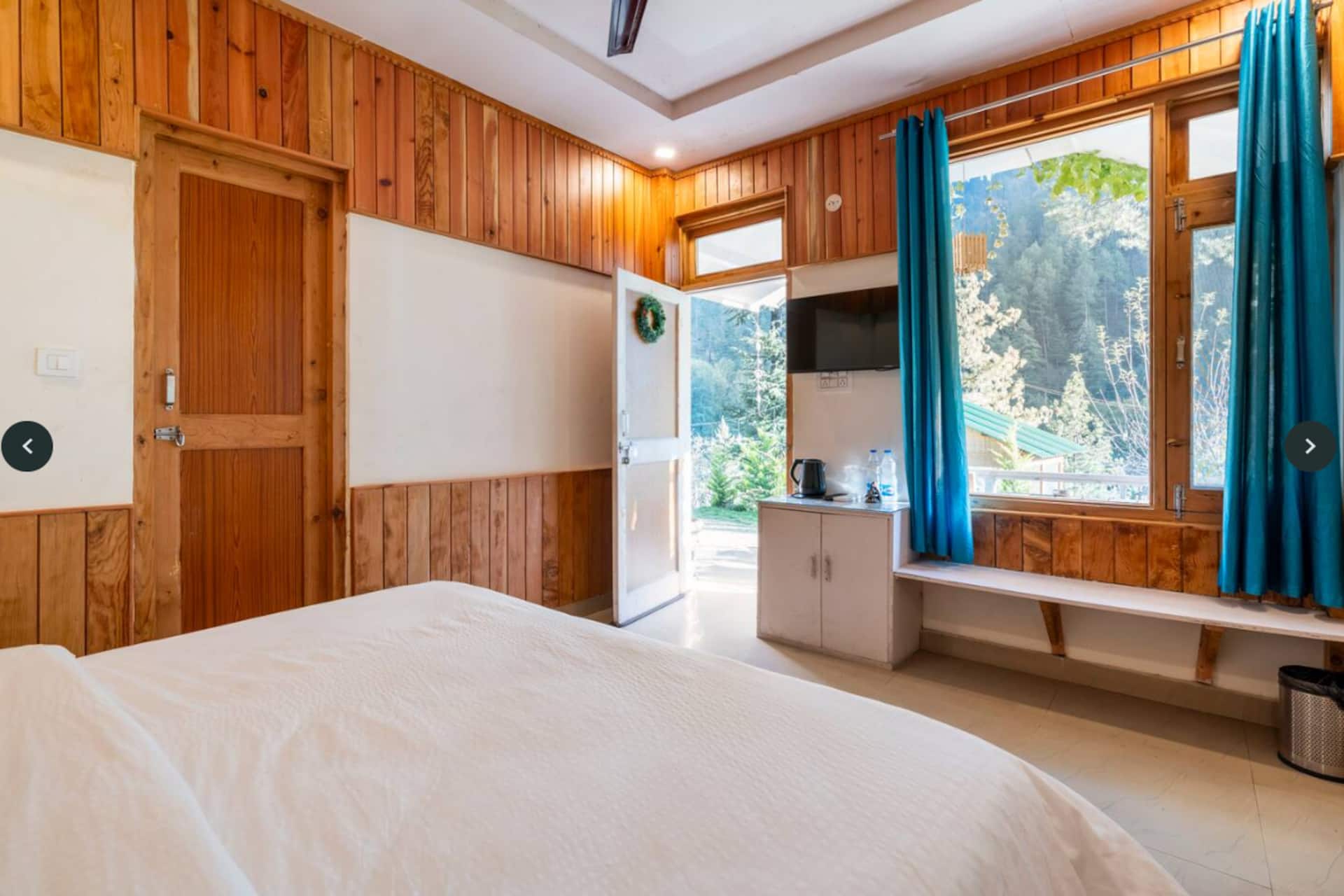 A timber cottage bedroom with a view of the pines